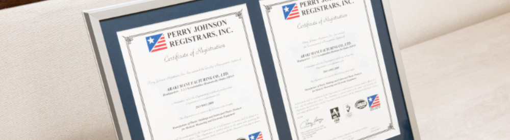 立て掛けられた2枚の額入り認証証書(PERRY JOHNSON REGISTRARS INC.)のクローズアップ