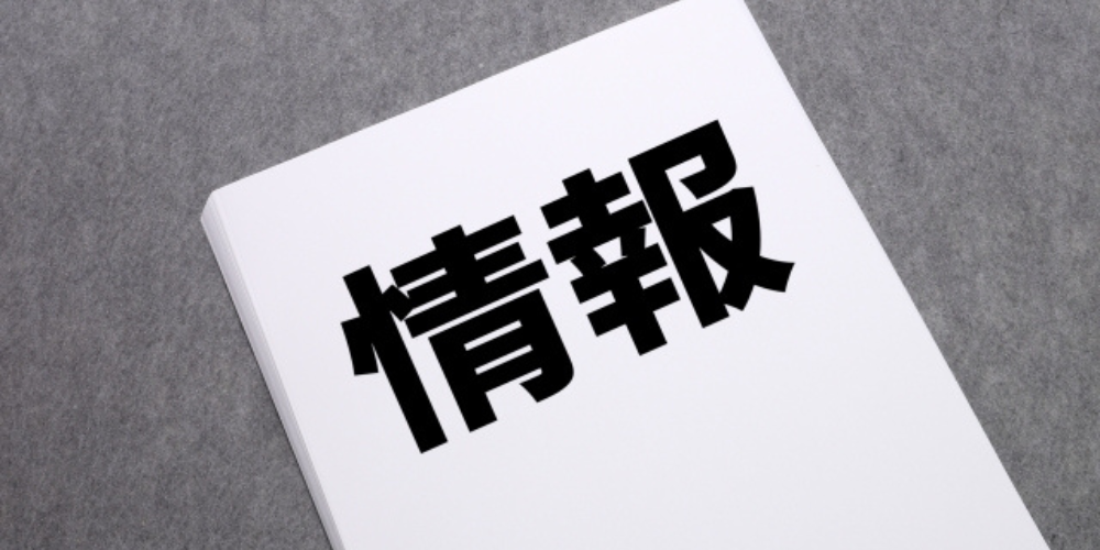「情報」と書かれた白い紙が斜めに置かれているイメージ