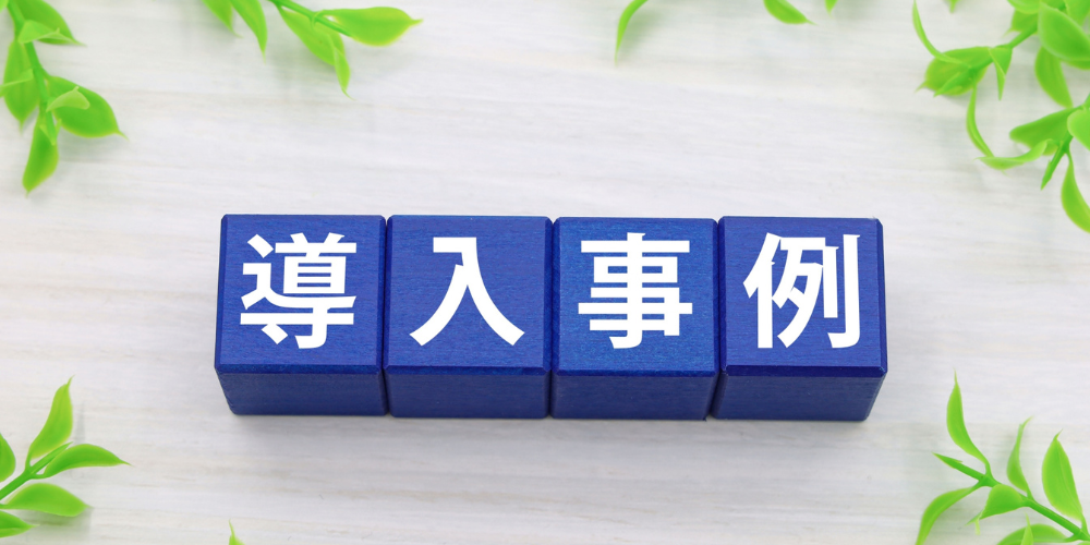 「導入事例」と書かれた青いブロックと緑の葉の装飾
