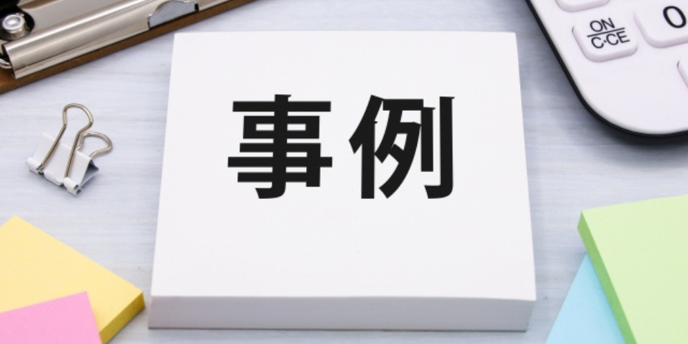 白いメモに「事例」と書かれており、周囲には文房具や付箋が置かれている