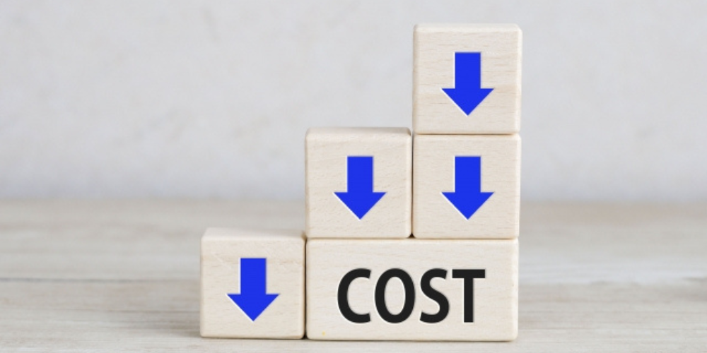 積み木の上に青い下向き矢印と「COST」の文字があり、コスト削減の視覚的表現