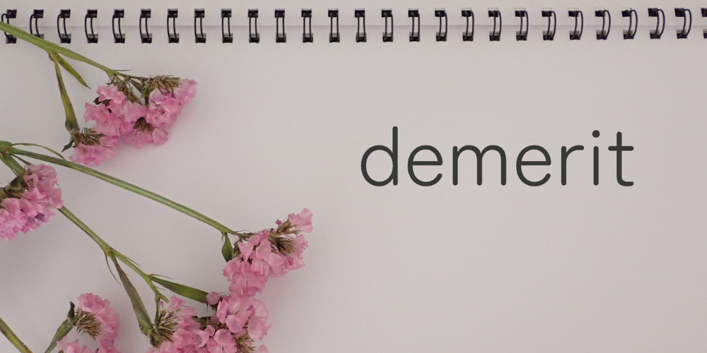 「demerit」の文字が書かれたノートとピンクの花の装飾がされたシンプルな背景