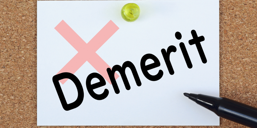 ノートに「demerit」と書かれており、ピンクの花が添えられている画像