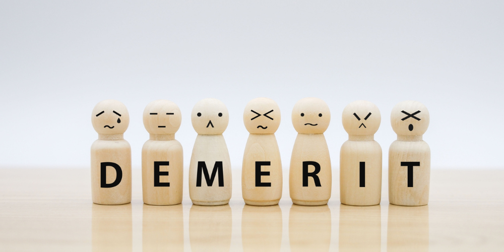 さまざまな表情の木製ピースで「DEMERIT」の文字を作ったデメリット(短所)のビジュアル