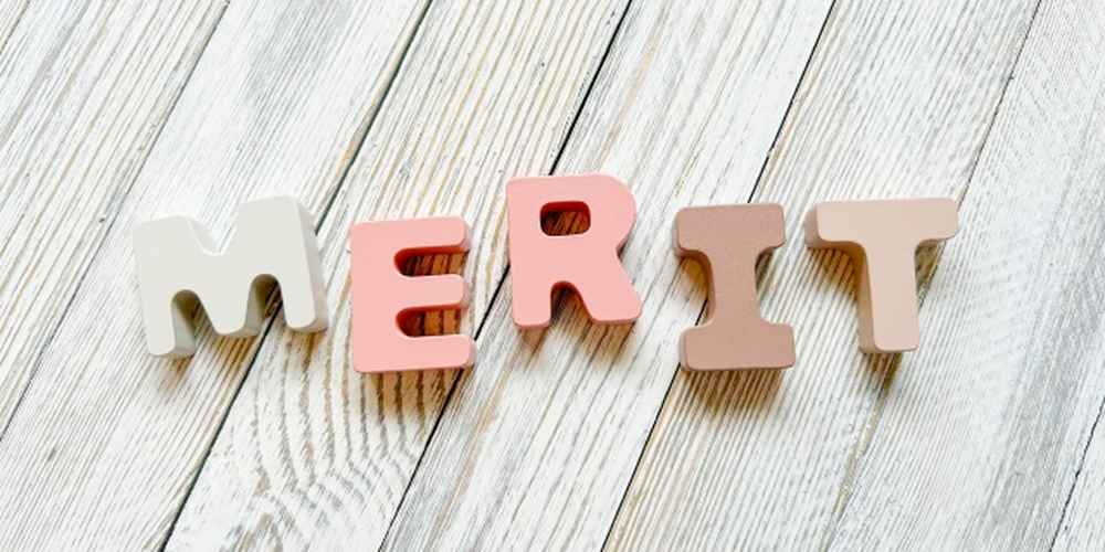 「木目調の背景に並んだカラフルな『MERIT』の文字ブロック、利点や魅力を伝えるイメージ」
