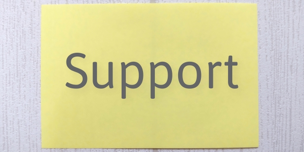 「黄色い紙に『Support』と書かれたシンプルなイメージ、サポート体制や支援サービスを示すビジュアル」