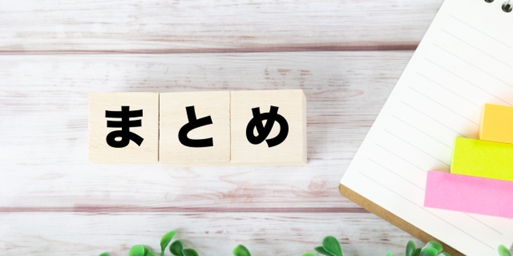 「木製ブロックに『まとめ』と書かれた文字とノート、記事や内容の締めくくりを表現するイメージ」