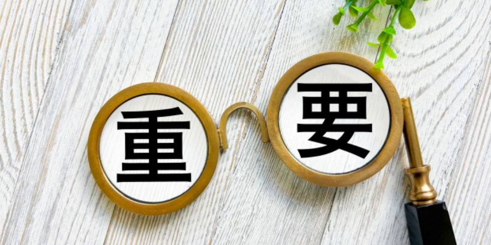 木目の背景に置かれた丸眼鏡のレンズ内に「重要」の文字があり、上部に植物が添えられた構成