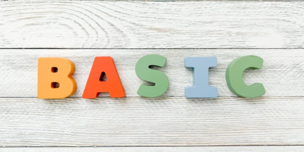 木目の背景にカラフルなアルファベットブロックで「BASIC」と並べられたシンプルな構成