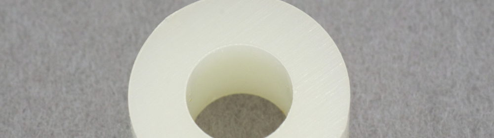 白い円形のプラスチックスペーサー部品が灰色の背景上に置かれている様子