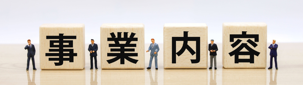 事業内容を表す木製ブロックとスーツ姿のビジネスパーソンのフィギュア