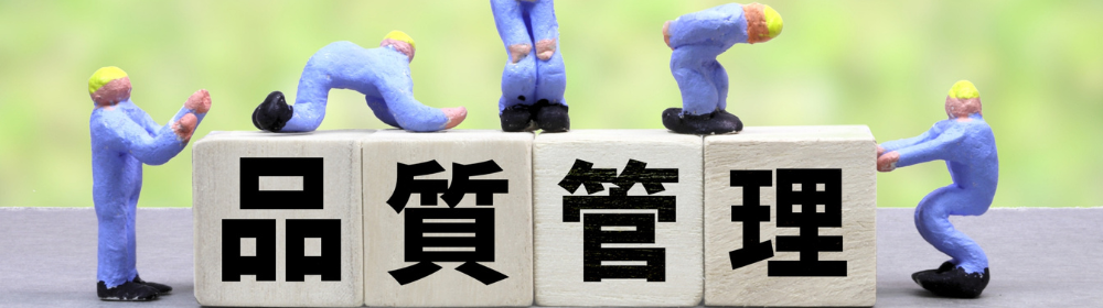 品質管理の文字が書かれた積み木の上で作業している作業員の人形