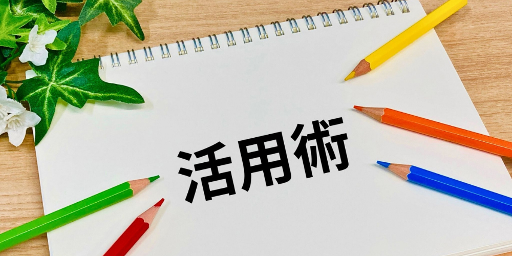 ノート中央に「活用術」と書かれ、周囲に色鉛筆が並べられている構図