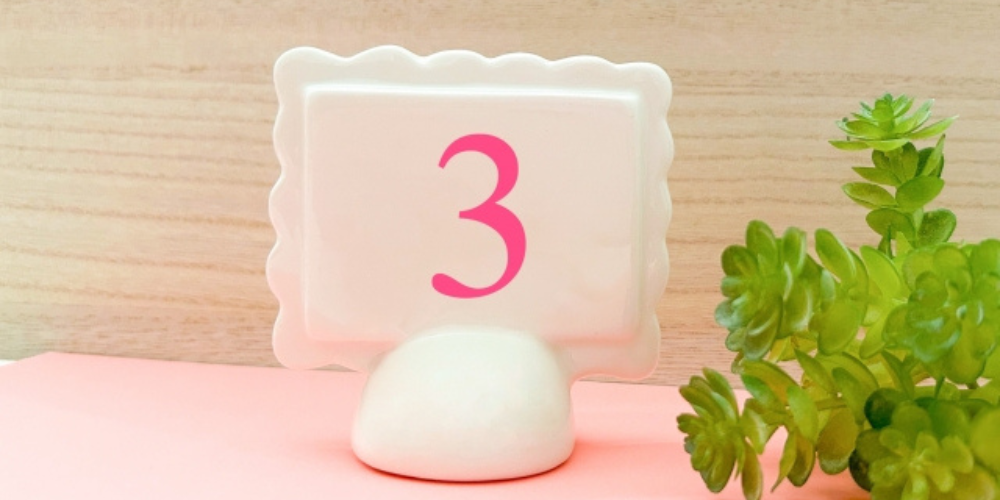 ピンク色の「3」と観葉植物を添えた白い卓上スタンド