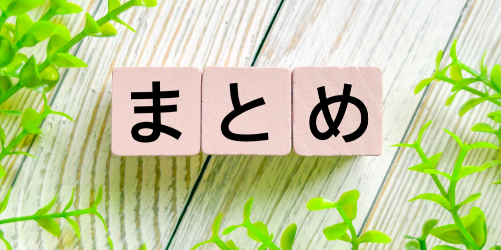 木製ブロックに書かれた「まとめ」の文字と緑の植物、木目の背景