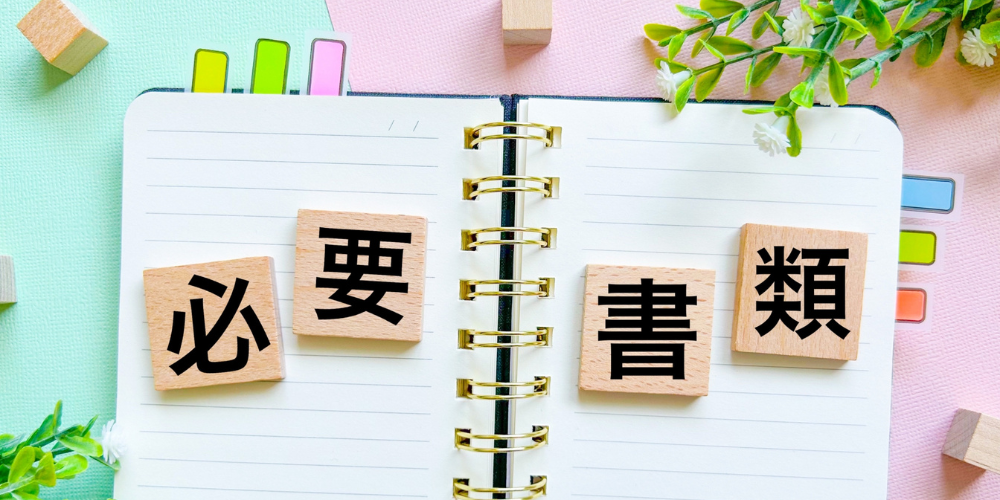「必要書類」の文字ブロックが並べられたノートとカラフルな背景