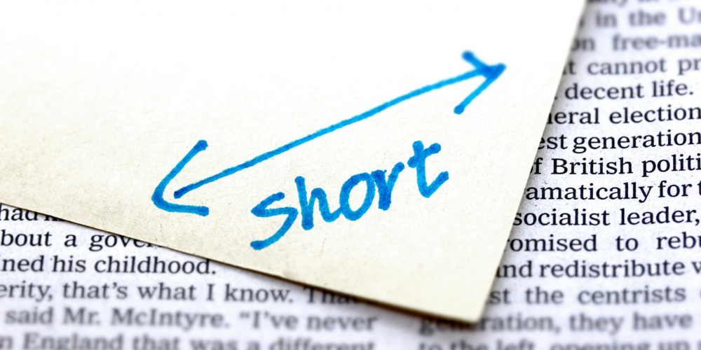 「short」と青い矢印が書かれた紙と英字新聞の一部