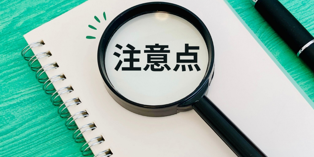 拡大鏡を通して「注意点」と書かれたノートを見る構成