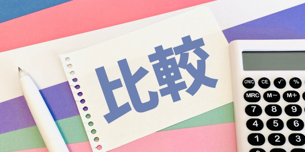 「比較」と書かれた紙と電卓が並んでいるイメージ