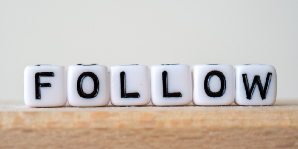 「FOLLOW」と書かれた白いキューブ型のブロックが木の台の上に並べられている