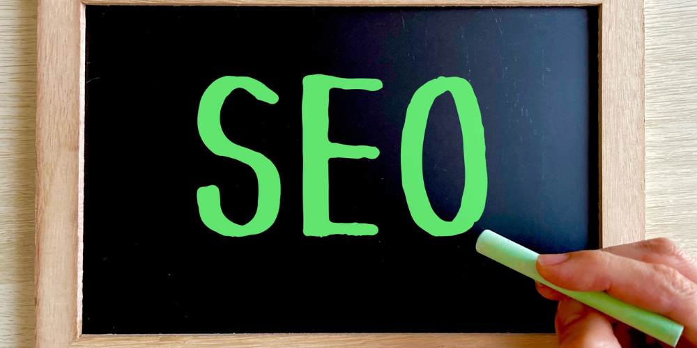 黒板にチョークで書かれた「SEO」の文字と手に持たれたチョーク