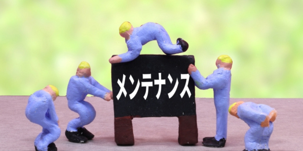 ミニチュア人形が「メンテナンス」と書かれた黒板を囲んで作業する様子