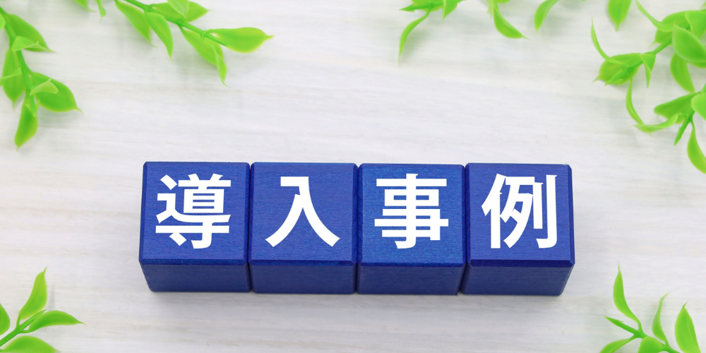  導入事例と書かれた青いブロックと緑の装飾
