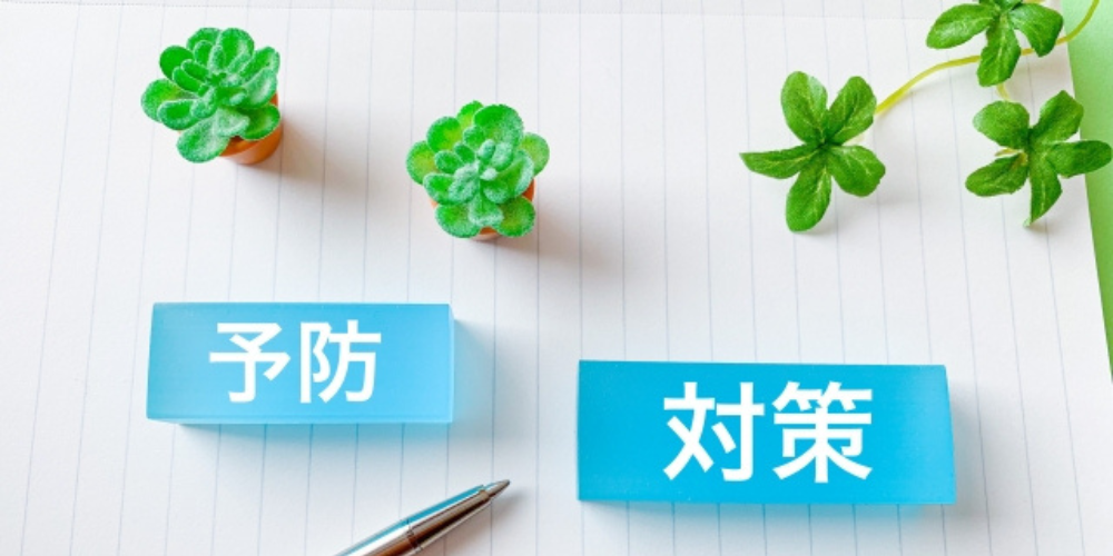 ノートの上に「予防」「対策」と書かれた青いブロックと緑のクローバー