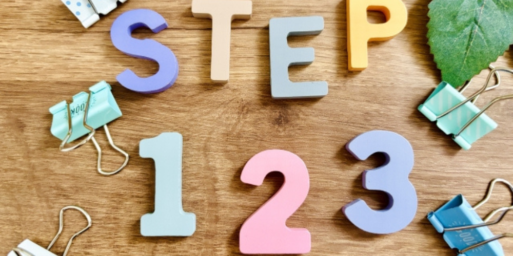 木製のデスクに並べられたカラフルな文字ブロック「STEP 123」
