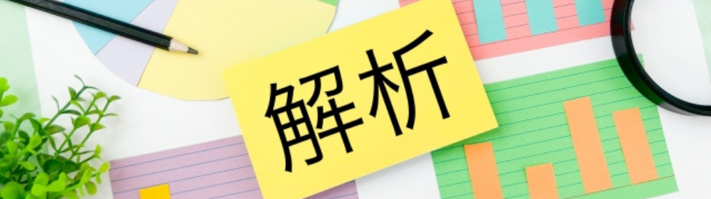 カラフルなグラフや資料の上に「解析」と書かれた黄色のカードが置かれているビジネスイメージ