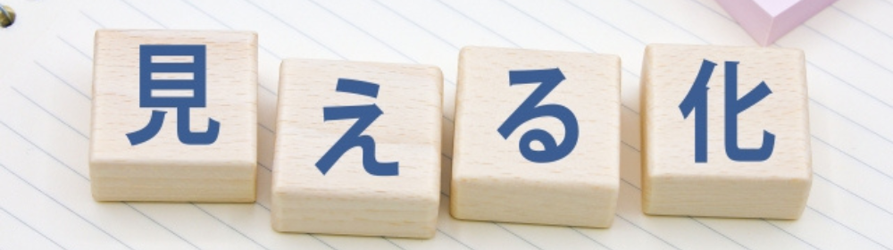 ノートの上に「見える化」と書かれた木製ブロックが並べられた画像