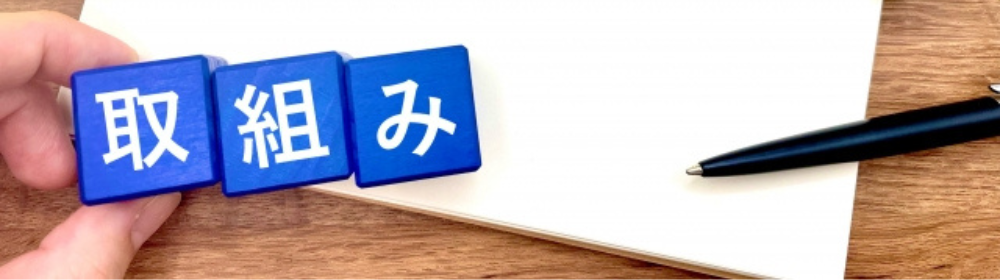  青いブロックに「取組み」の文字が書かれ、メモ用紙とペンが横に置かれた画像