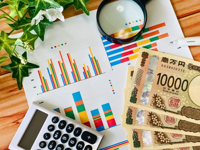 計算機　グラフが書かかれた資料とお札