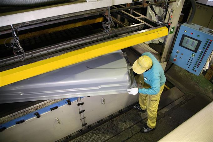 真空成形機器から大きなプラスチックトレイを取り出している様子